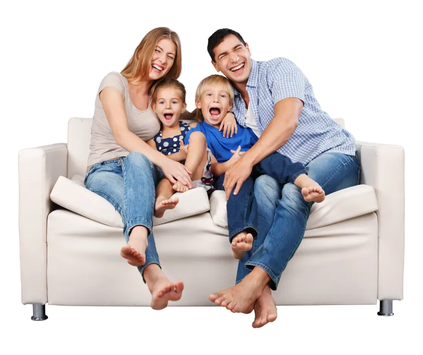 A happy family of four—two parents and two young children—laughing together on a white couch, reflecting the joyful, supportive spirit of Homeopathy at Home.